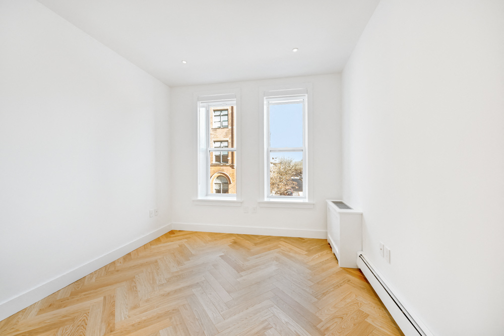 a living room with a wood floor and two windows